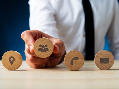 Business customer service representative placing four wooden cut circles with contact and information icons on them in a row.