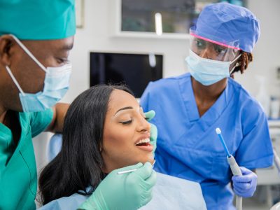 Girl with open mouth during a dental visit, dentist and assistant at work, dental health concept.