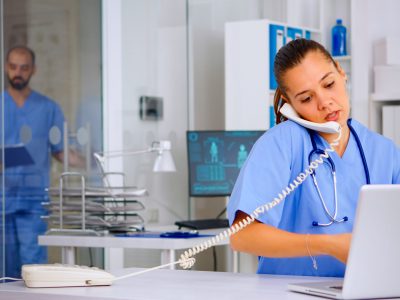 Medical assistant speaking at phone with patient analysing radiographics discussing the diagnosis, making new appointment. Healthcare physician, doctor nurse helping with telehealth communication