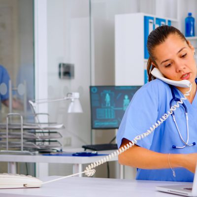 Medical assistant speaking at phone with patient analysing radiographics discussing the diagnosis, making new appointment. Healthcare physician, doctor nurse helping with telehealth communication